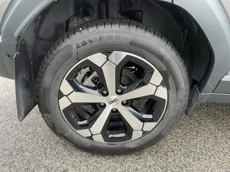 Gros plan sur la roue avant droite du Dacia Duster 1.6 Hybrid 140 cv gris schiste avec jante alliage bicolore.