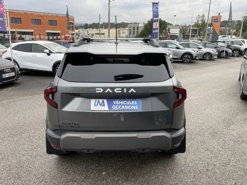 Vue arrière d'un Dacia Duster 1.6 Hybrid gris schiste 2025, avec logo DACIA en lettres blanches et plaque "Véhicules Occasions".