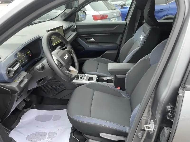Vue intérieure côté conducteur du Dacia Duster 1.6 Hybrid gris schiste, montrant sièges et tableau de bord moderne.