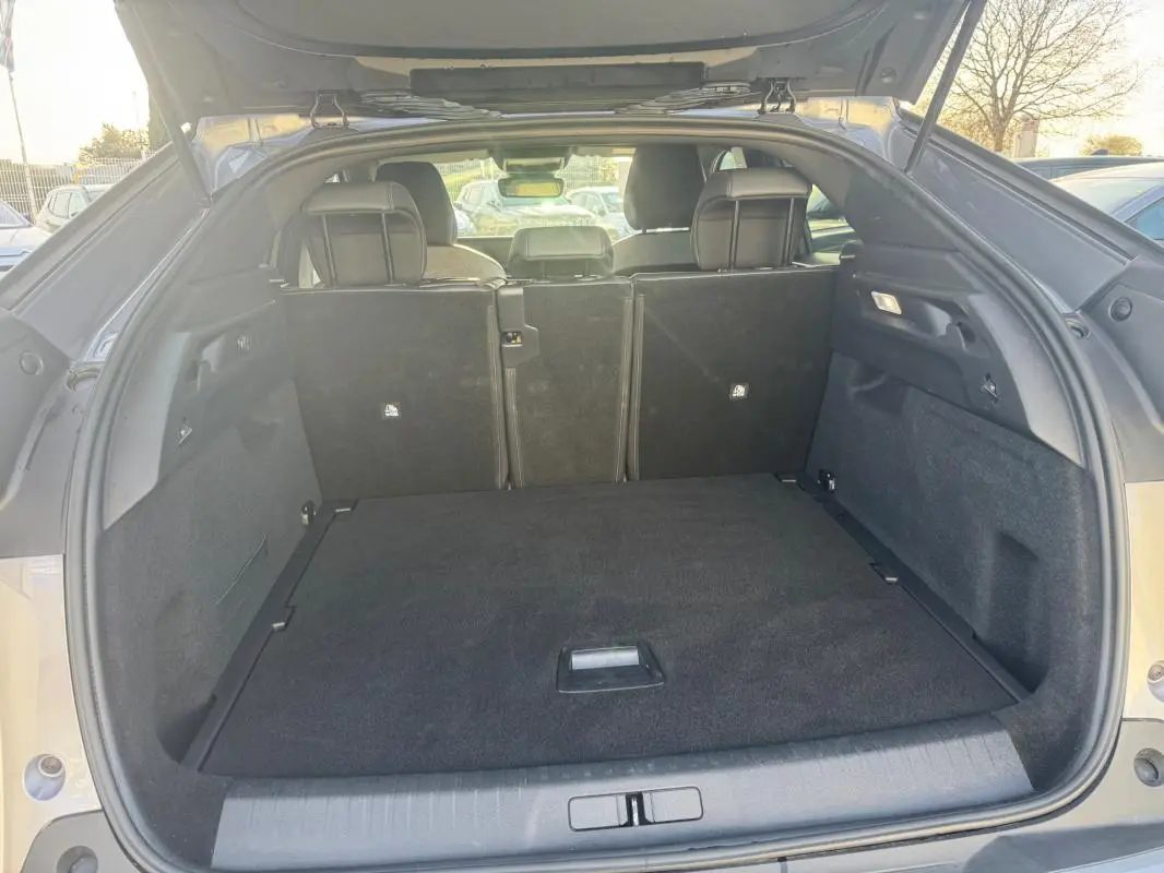 Coffre ouvert vu de l'arrière d'un Peugeot 3008 Hybrid gris, montrant l'espace de chargement et les sièges arrière.