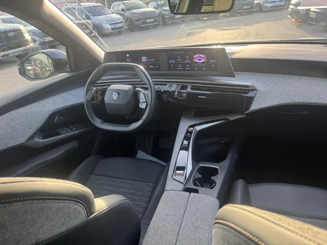 Vue intérieure avant du Peugeot 3008 Hybrid gris 2025, mettant en valeur le cockpit numérique et la console centrale design.