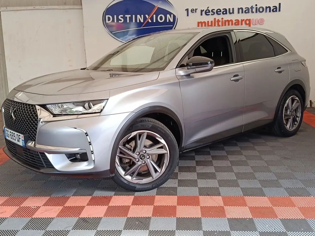 DS7 Crossback gris clair en 3/4 avant droit, avec calandre distinctive et jantes alliage modernes.