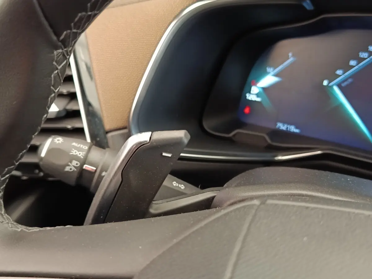 Gros plan sur le volant cuir et palettes de commande du DS7 Crossback E-TENSE 225, tableau de bord numérique en arrière-plan.