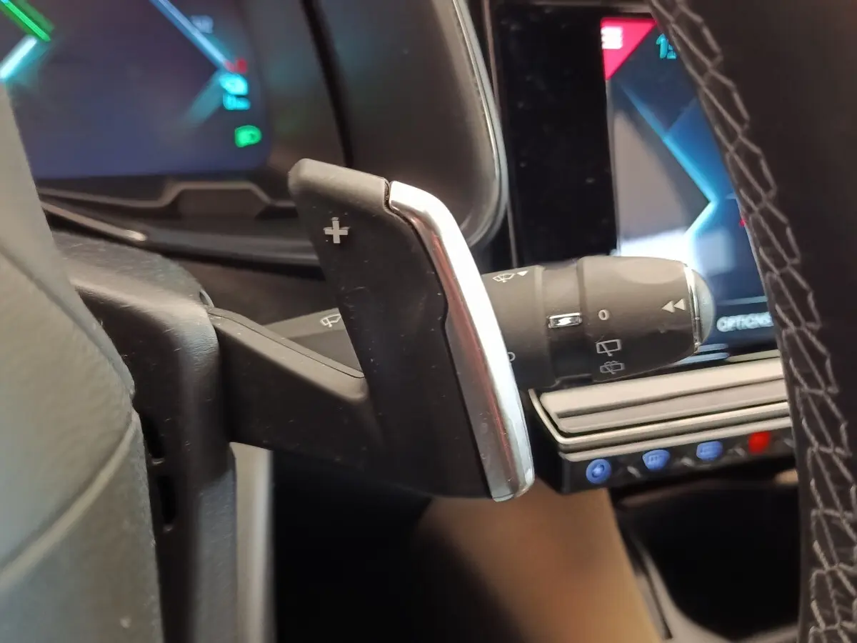 Gros plan sur la palette de changement de vitesse au volant cuir du DS7 Crossback E-TENSE 225, avec écran tactile en arrière-plan.