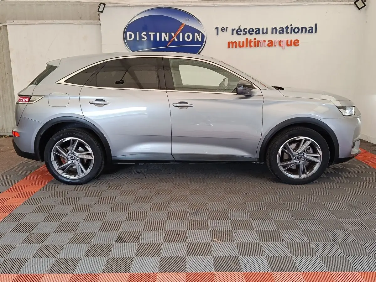 Vue de profil côté gauche d’un DS7 Crossback E-TENSE 225 Business gris clair, avec jantes alliage et vitres teintées.