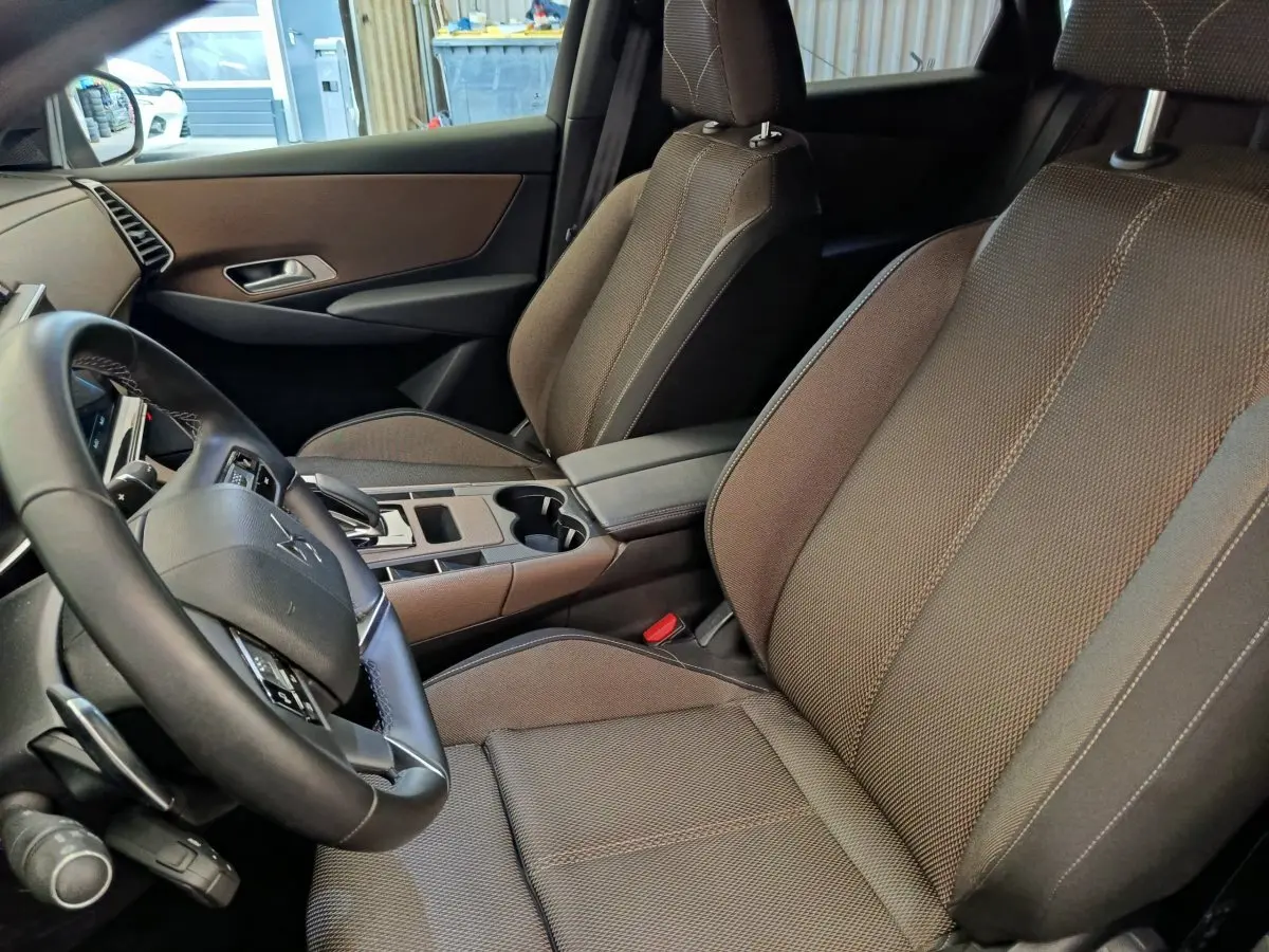 Vue intérieure côté conducteur du DS7 Crossback E-TENSE 225 Business 2022, sièges tissu marron et volant cuir multifonctions.