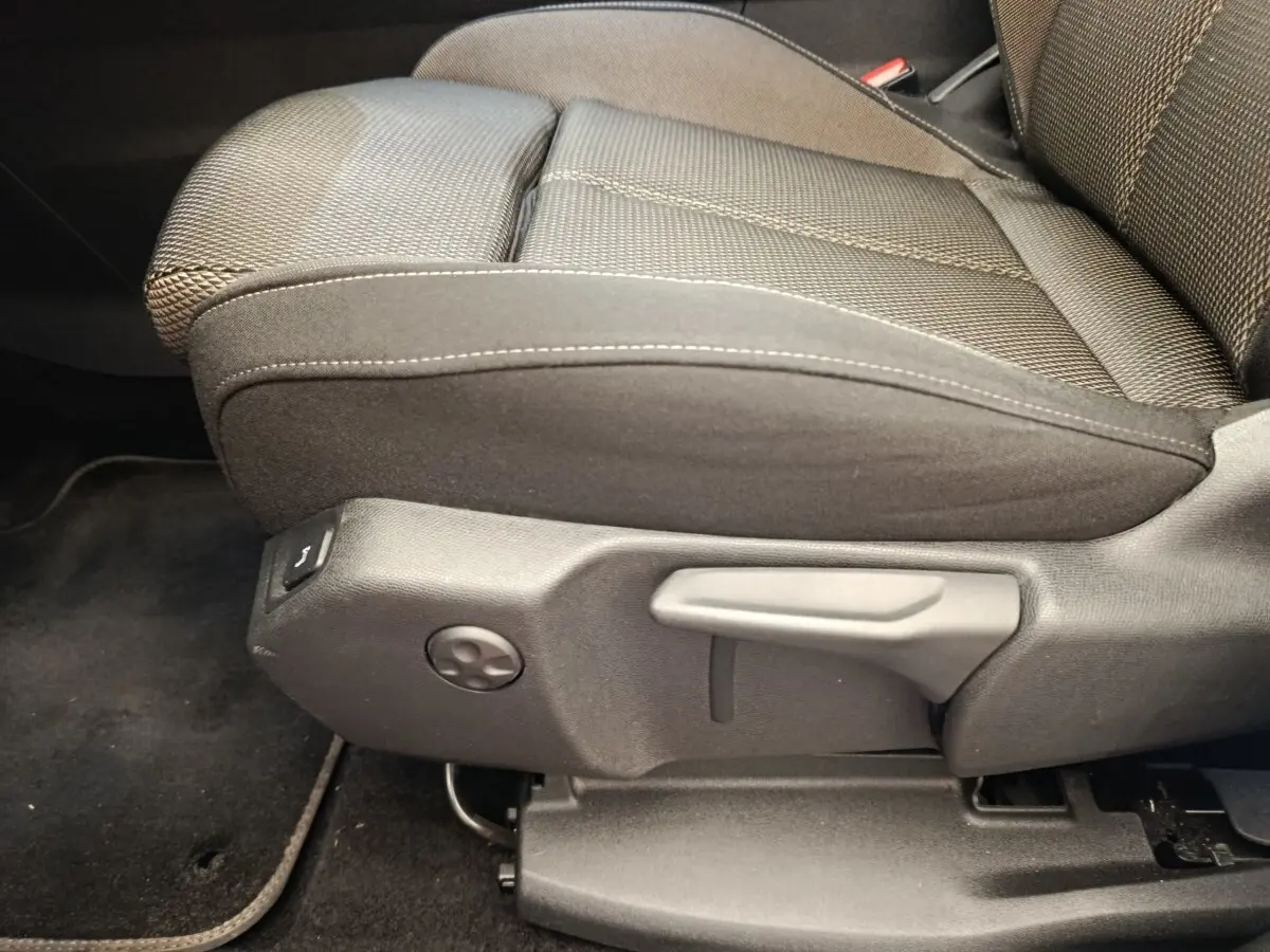 Gros plan sur le siège avant droit en tissu noir du DS7 Crossback E-TENSE 225 BUSINESS, montrant les commandes de réglage manuel.