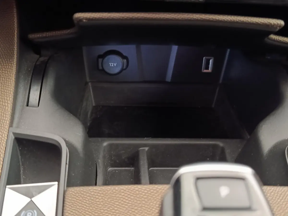 Gros plan sur la console centrale du DS7 Crossback E-TENSE 225 Business avec prise 12V et rangement noir.