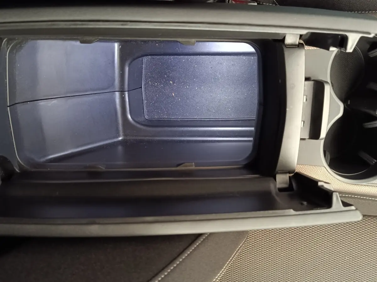 Vue plongeante sur l'accoudoir central ouvert du DS7 Crossback E-TENSE 225 Business, intérieur beige et rangement vide.