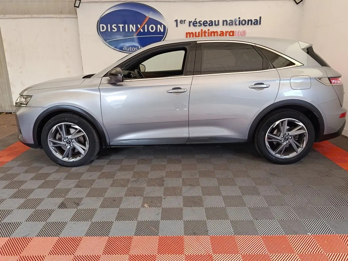 Vue de profil côté gauche d’un DS7 Crossback E-TENSE 225 Business gris clair, avec jantes alliage et vitres teintées.