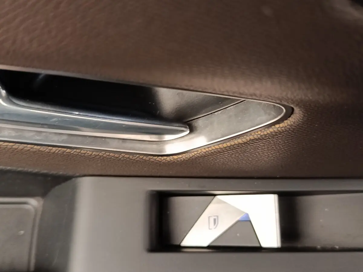 Bouton de commande de lève-vitre en métal brossé sur porte intérieure en cuir marron du DS7 Crossback gris clair.