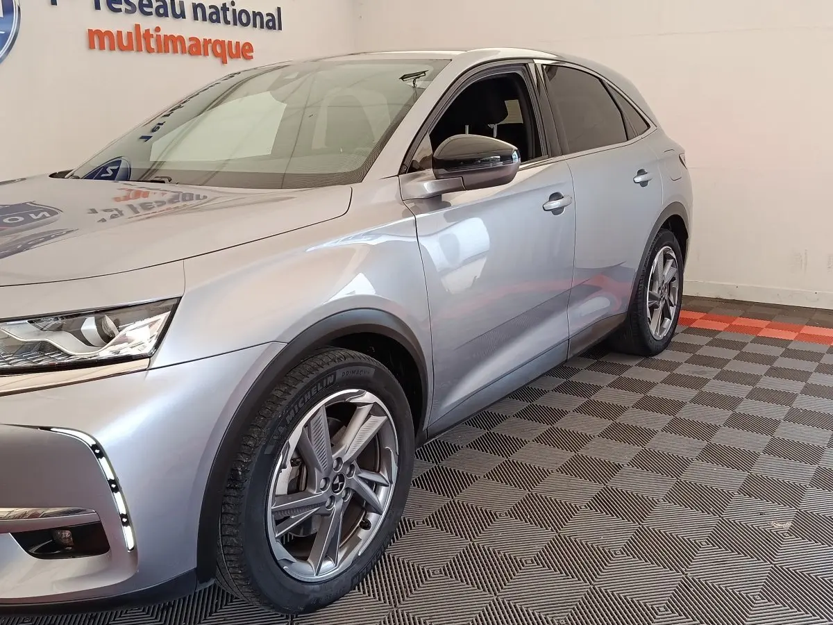 Vue 3/4 avant droite d'un DS7 Crossback E-TENSE 225 Business gris clair avec jantes alliage et feux LED allumés.