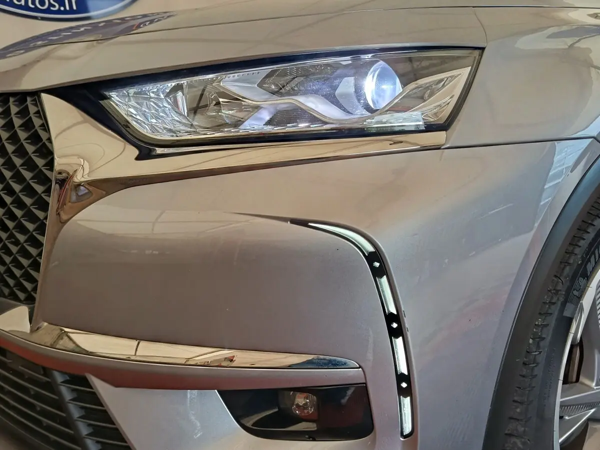 Gros plan sur l'avant droit gris clair du DS7 Crossback E-TENSE 225 avec phare LED allumé et signature lumineuse verticale.