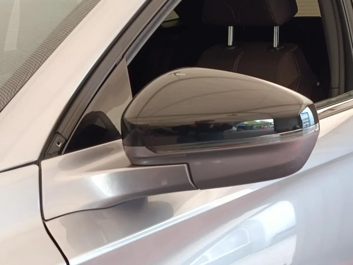 Rétroviseur droit gris clair du DS7 Crossback E-TENSE 225 BUSINESS, vue rapprochée sur la portière et l'intérieur cuir.