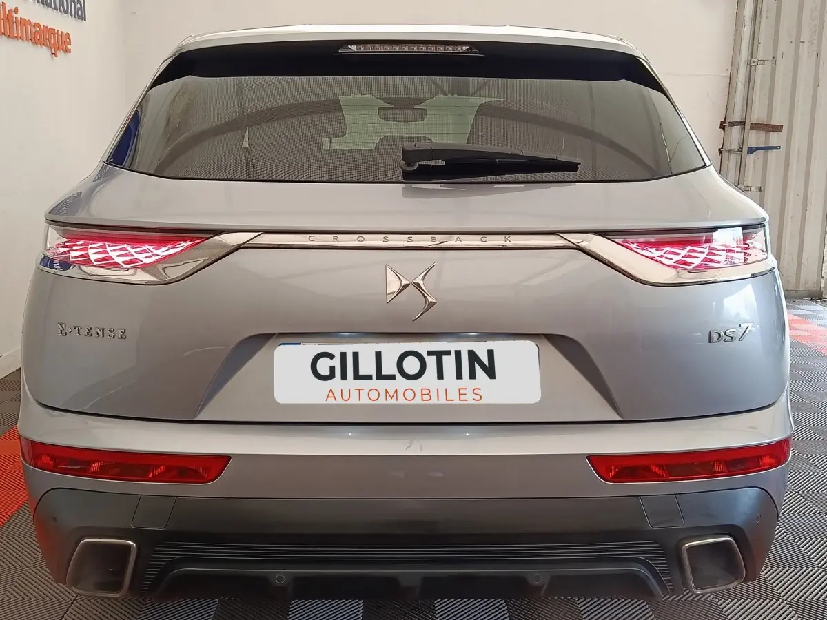 Vue arrière d'un DS7 Crossback gris clair avec feux LED allumés et logo DS centré sur le hayon.