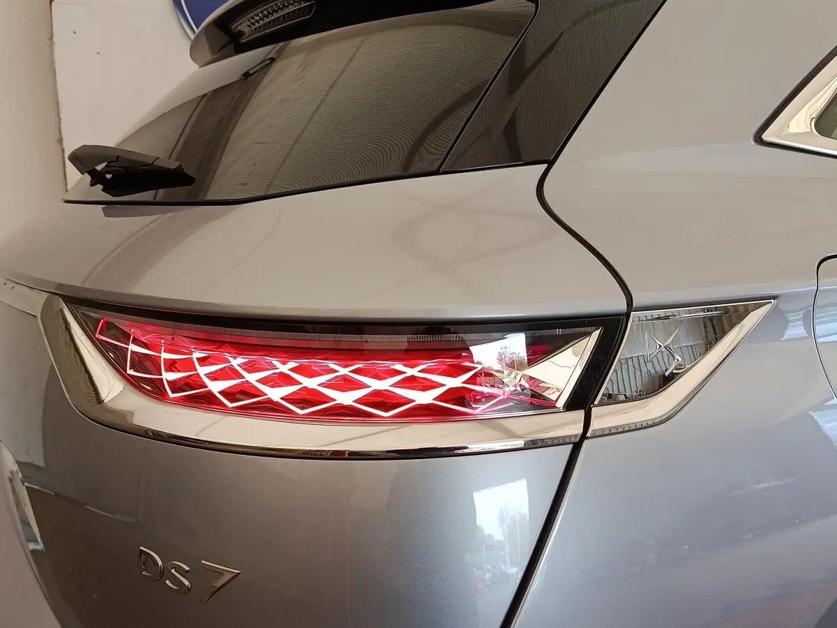 Feu arrière droit allumé sur DS7 Crossback gris clair, vue rapprochée du coin arrière droit avec lunette arrière.