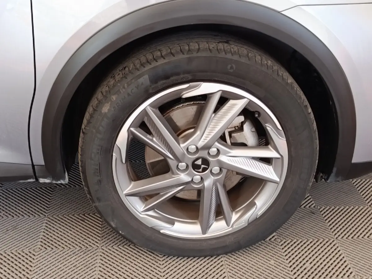 Gros plan sur la roue avant gauche d’un DS7 Crossback gris clair, mettant en valeur la jante alliage au design moderne.