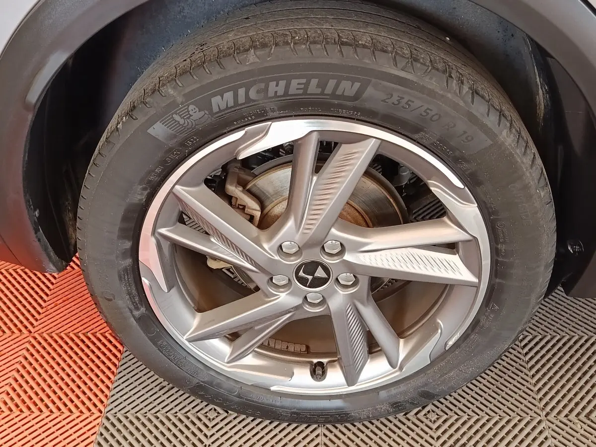 Gros plan sur la roue avant droite gris clair du DS7 Crossback E-TENSE 225 BUSINESS avec jante alliage et pneu Michelin.