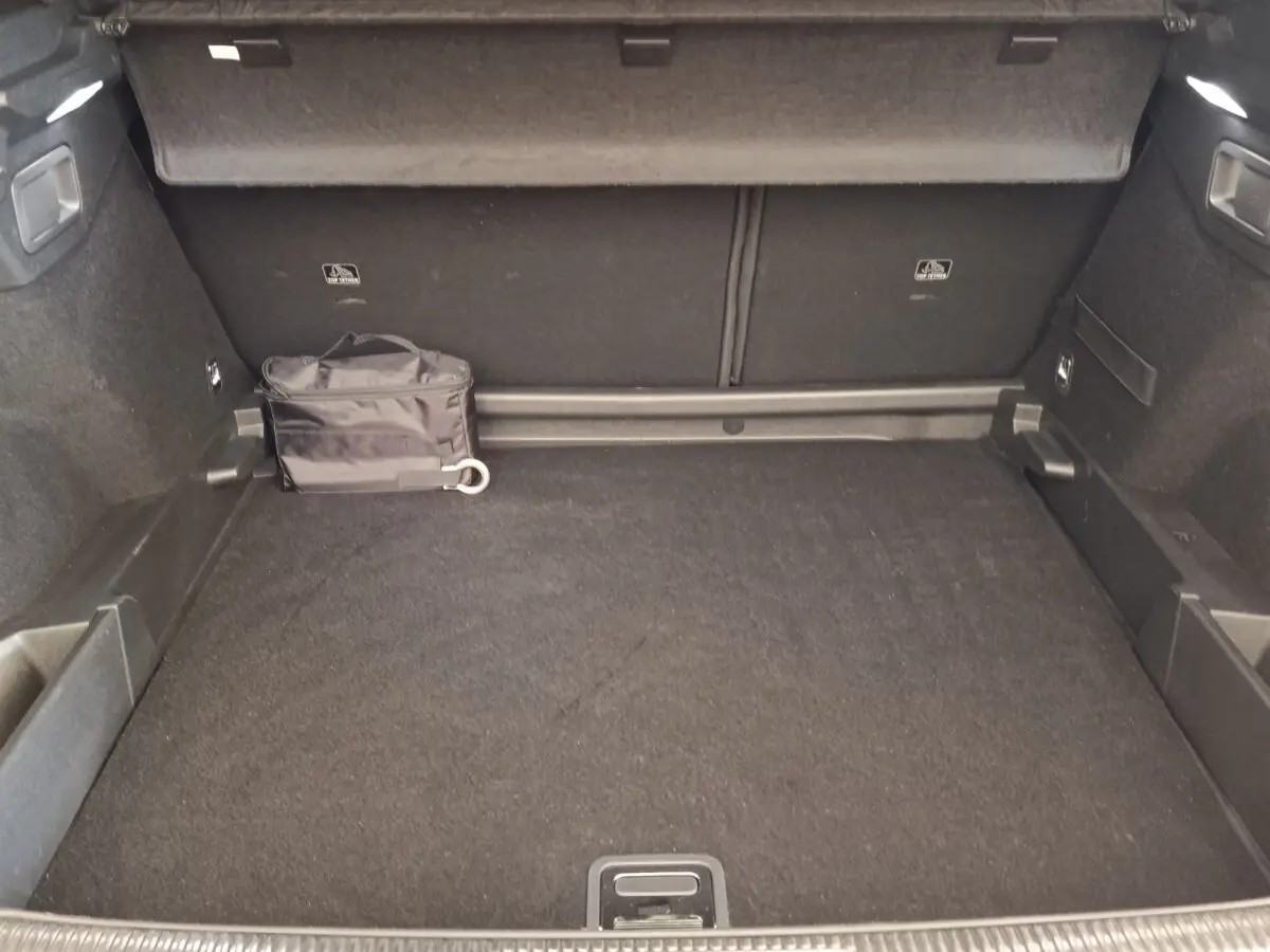 Vue intérieure du coffre spacieux du DS7 Crossback E-TENSE 225 Business, avec tapis noir et sac de rangement.