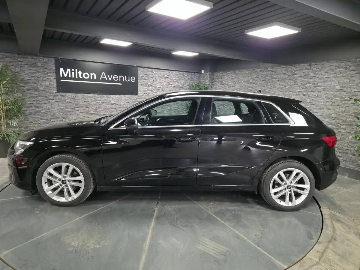 Audi A3 Sportback noire vue de profil côté gauche, avec jantes alliage 5 branches et calandre noire mate.