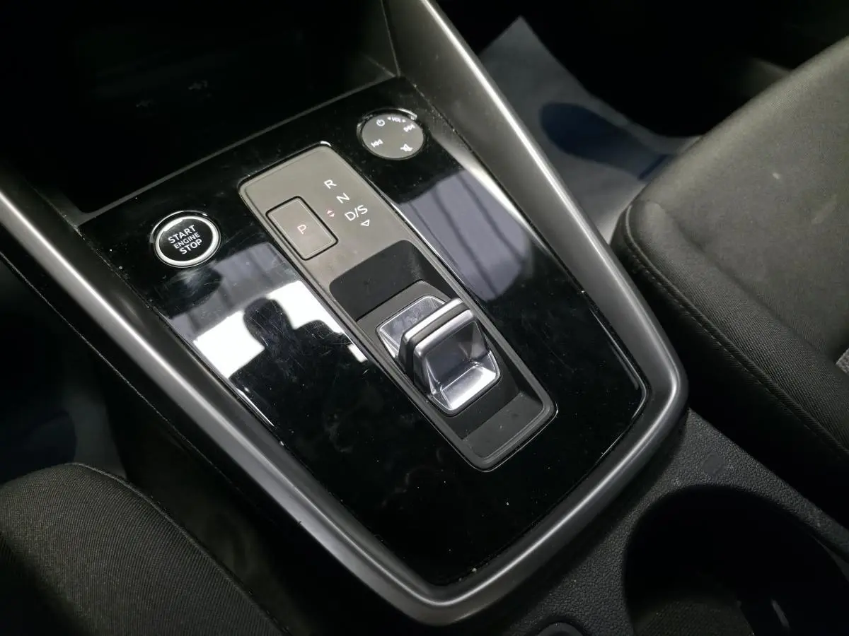 Vue rapprochée de la console centrale noire brillante de l’Audi A3 Sportback 2023 avec sélecteur de boîte auto et bouton start/stop.
