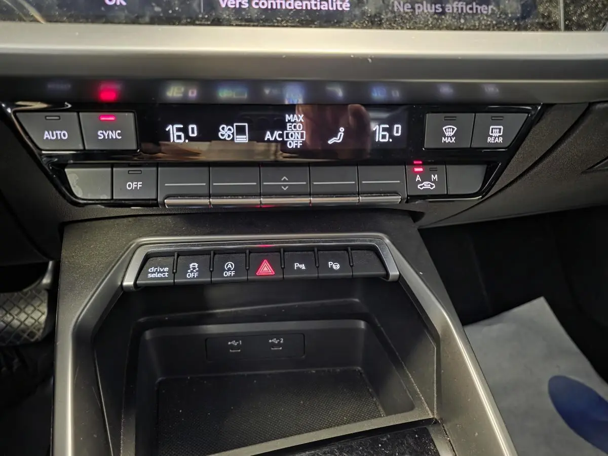 Gros plan sur la console centrale de l’Audi A3 Sportback 2023 avec commandes climatisation et boutons multifonctions.