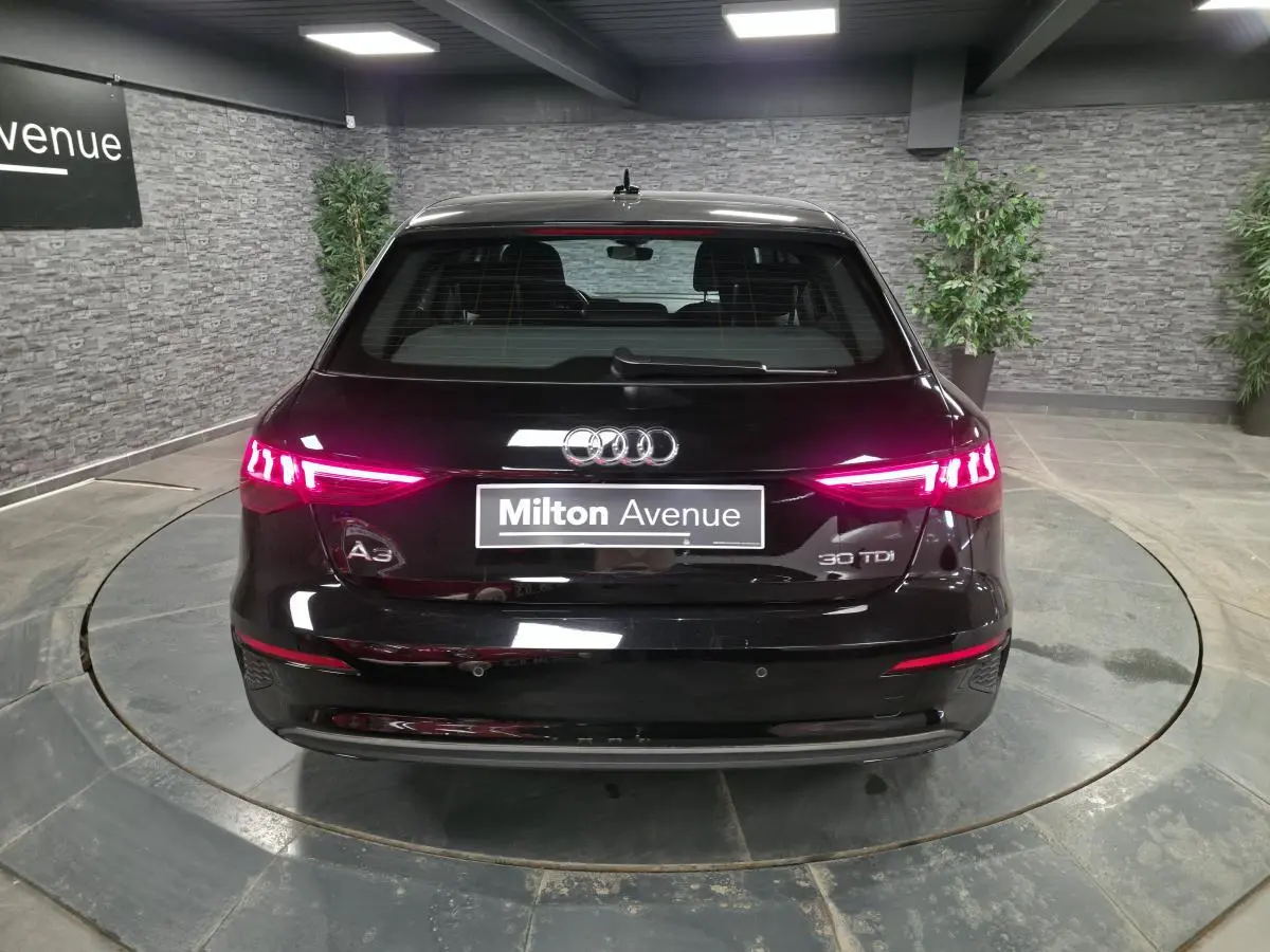 Vue arrière d'une Audi A3 Sportback noire 2023 avec feux LED allumés dans un showroom.