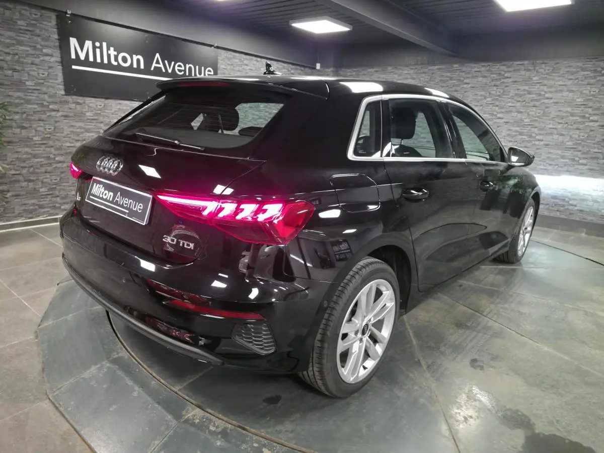 Audi A3 Sportback noir vue 3/4 arrière droit, feux LED allumés et jantes alliage 17 pouces visibles.