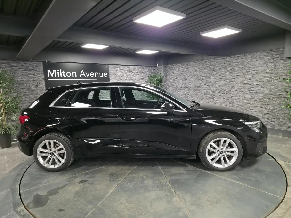 Audi A3 Sportback noir vue de profil côté gauche dans un showroom avec jantes alliage 5 branches.