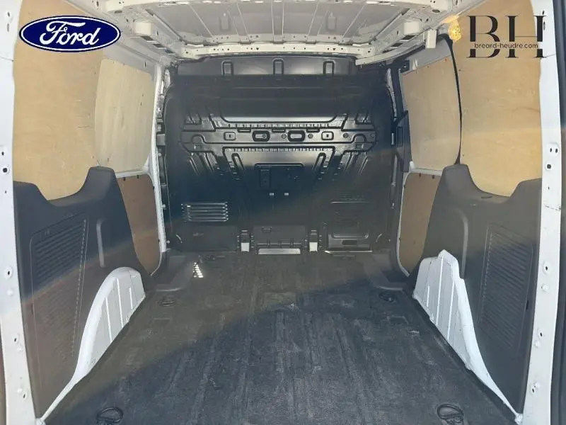Vue intérieure arrière du Ford Transit Connect blanc glacier, montrant l'espace de chargement avec cloison tôlée et plancher caoutchouc.