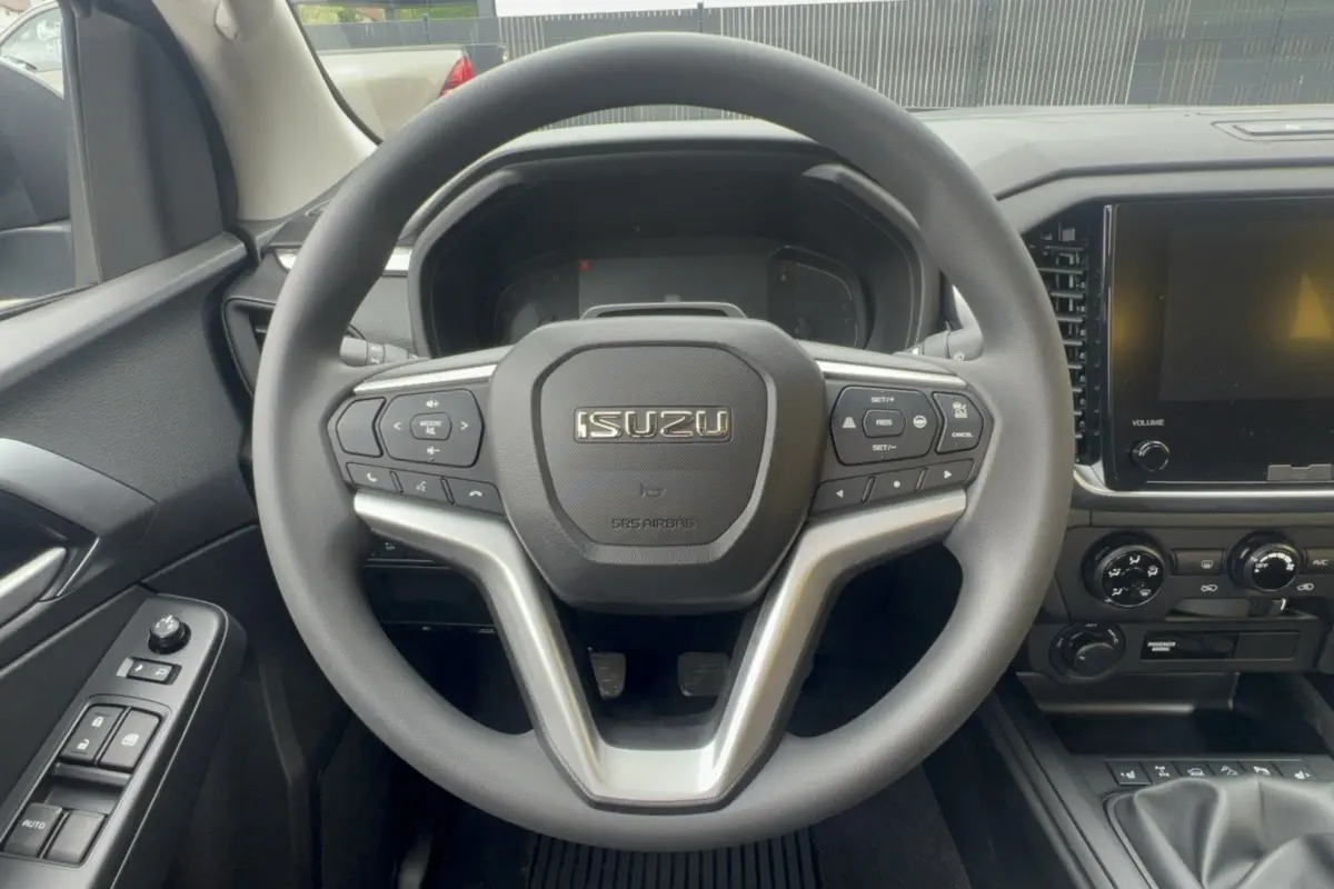 Vue rapprochée du volant multifonctions et tableau de bord noir de l'Isuzu D-MAX 2026 avec écran tactile et commandes au volant.