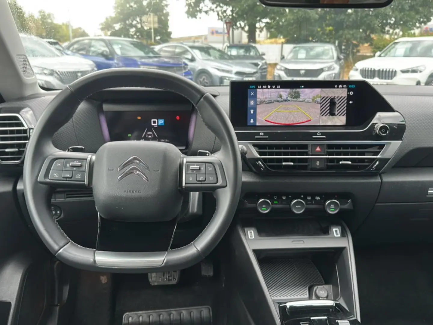 Intérieur de la Citroën C4 1.5 BlueHDi 130 gris, vue frontale sur le volant cuir et l'écran tactile affichant la caméra de recul.