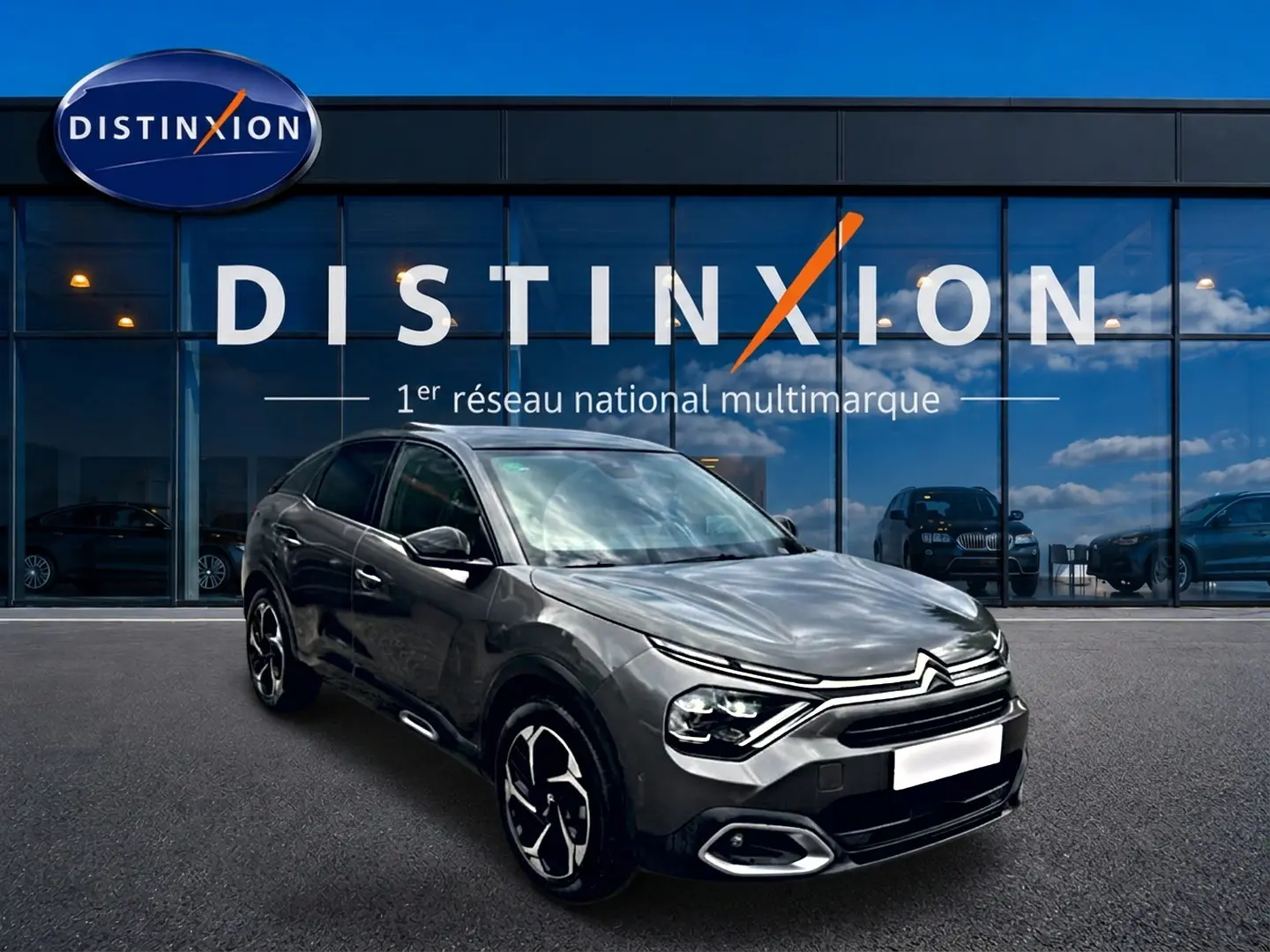 Citroën C4 gris vue 3/4 avant droit, avec jantes alu et phares LED, devant une vitrine Distinxion.