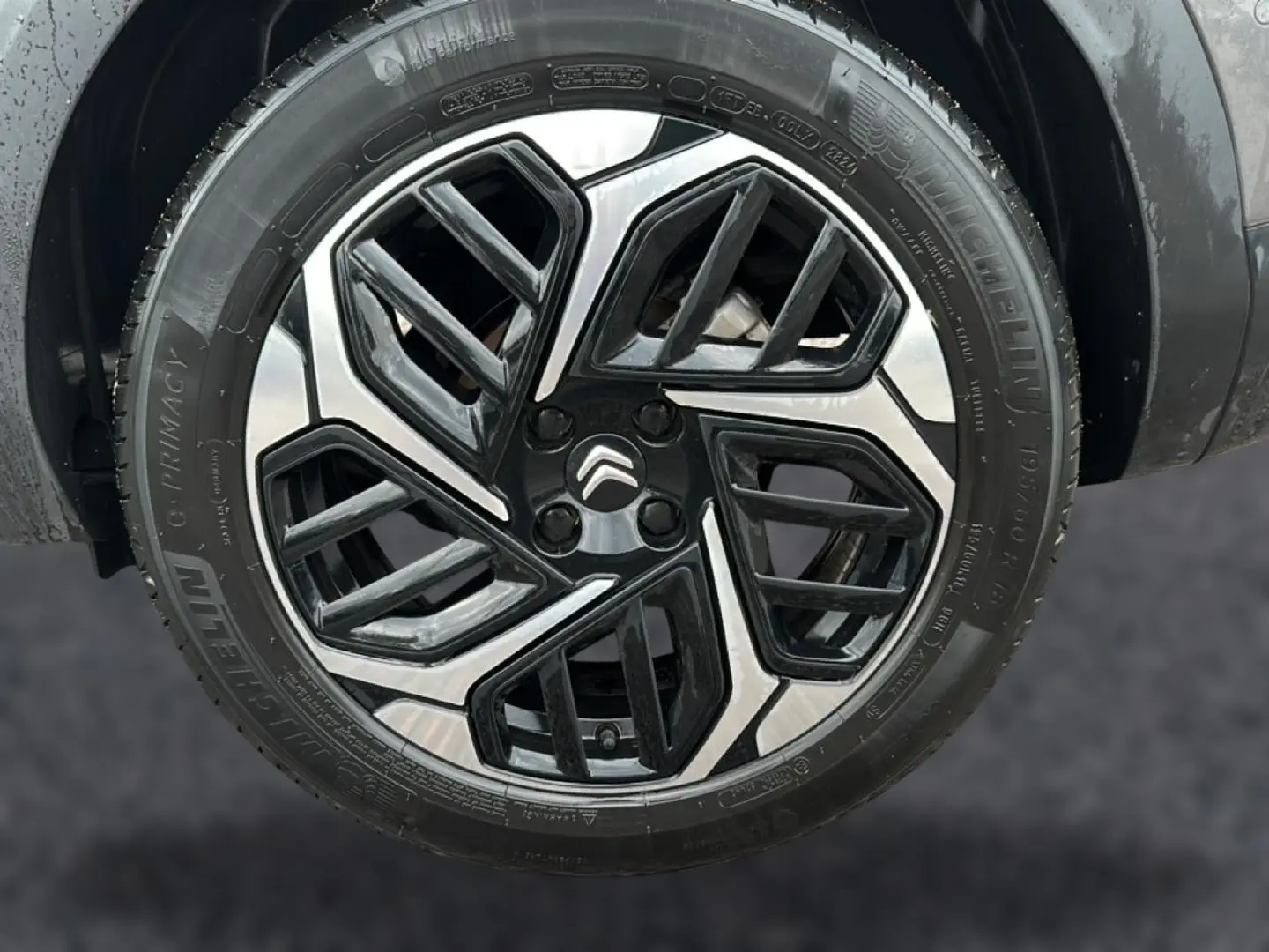 Gros plan sur la jante alu noire et argentée d'une Citroën C4 gris, avec logo Citroën au centre.