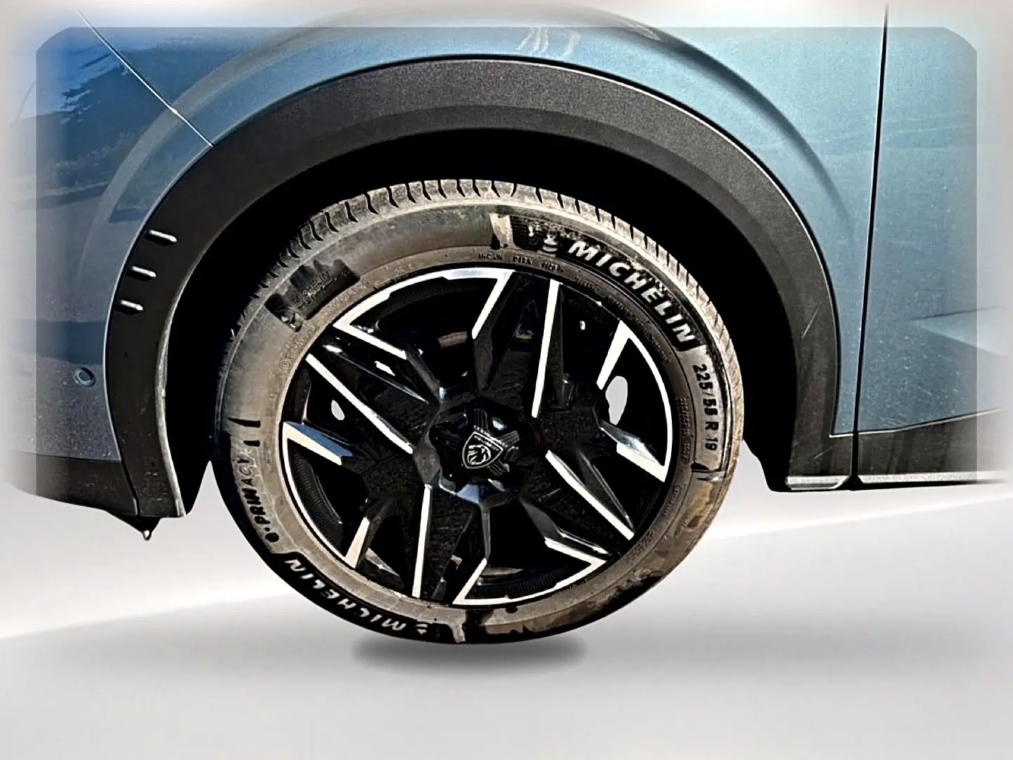 Gros plan sur la roue arrière droite du Peugeot 3008 bleu 2025 avec jante alliage noire et logo Peugeot central.