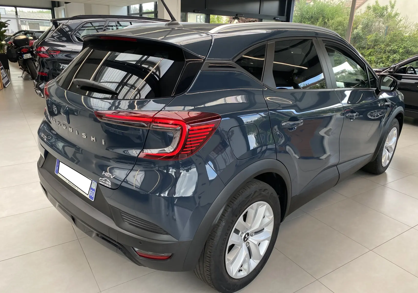 Vue 3/4 arrière droite du Mitsubishi ASX 2023 hybride en Steel Gray métallisé, avec feux arrière LED et jantes argentées.