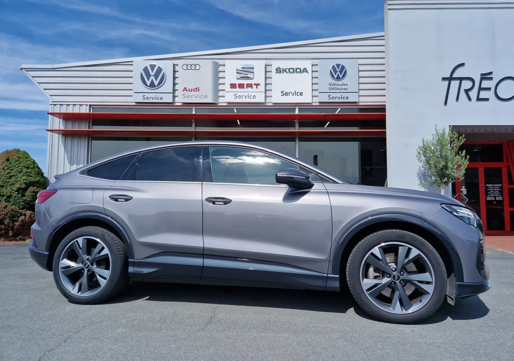 Profil côté gauche de l'Audi Q4 E-TRON Sportback gris thyphon 2022, avec jantes alliage et lignes fluides électriques.