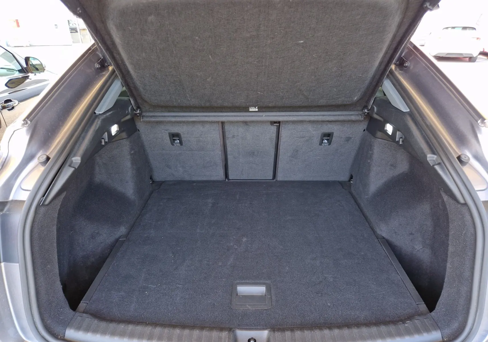Coffre ouvert de l'Audi Q4 E-TRON SPORTBACK gris thyphon, vue arrière montrant un espace de chargement propre et spacieux.