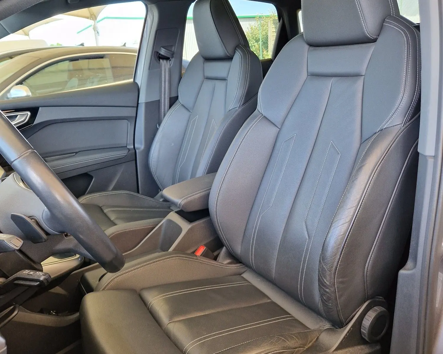 Vue intérieure côté conducteur de l'Audi Q4 E-TRON Sportback 50 quattro 2022 avec sièges cuir noir et toit panoramique.