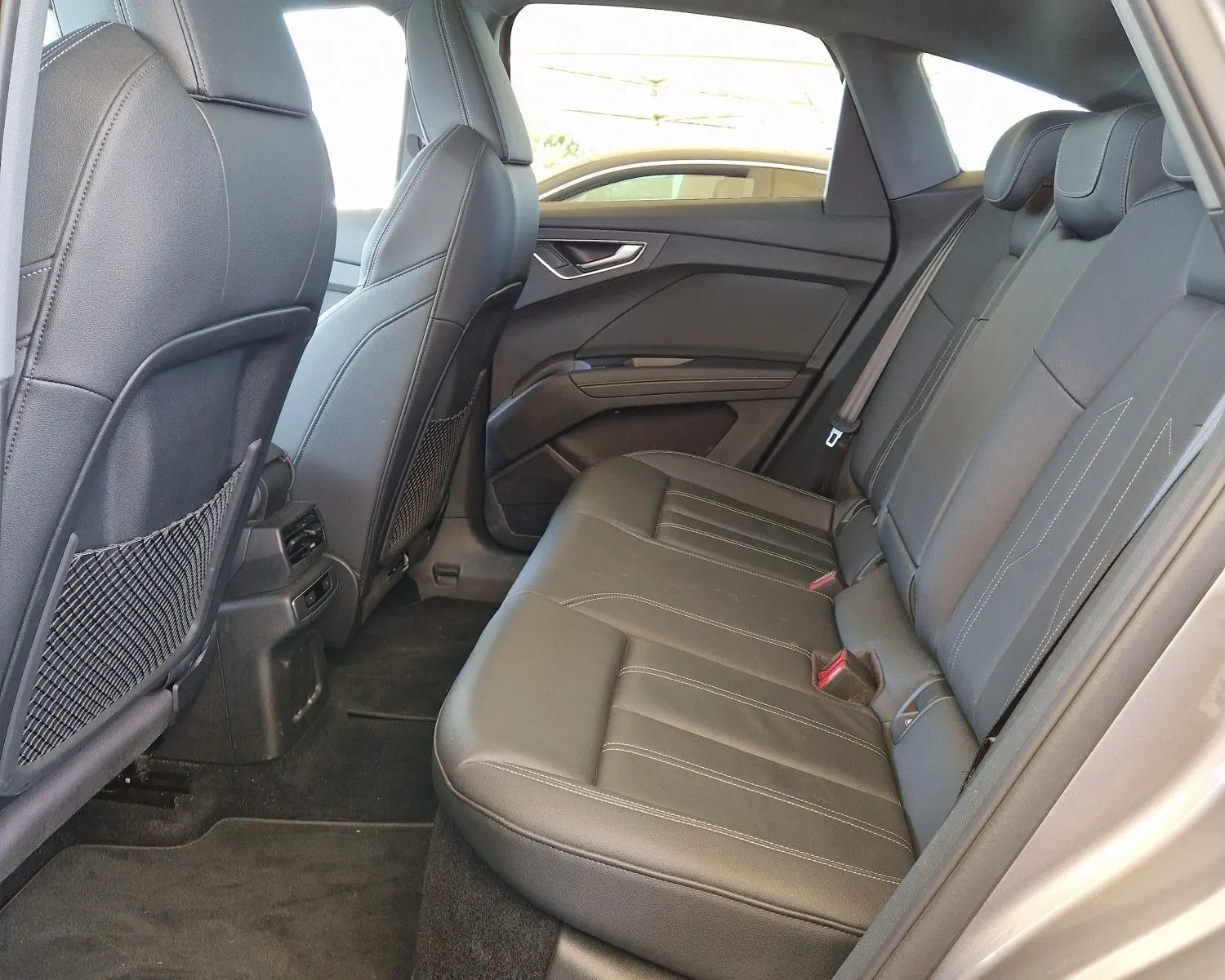 Vue intérieure arrière côté gauche de l'Audi Q4 E-TRON Sportback 50 quattro 2022 avec sièges cuir noir et toit panoramique.