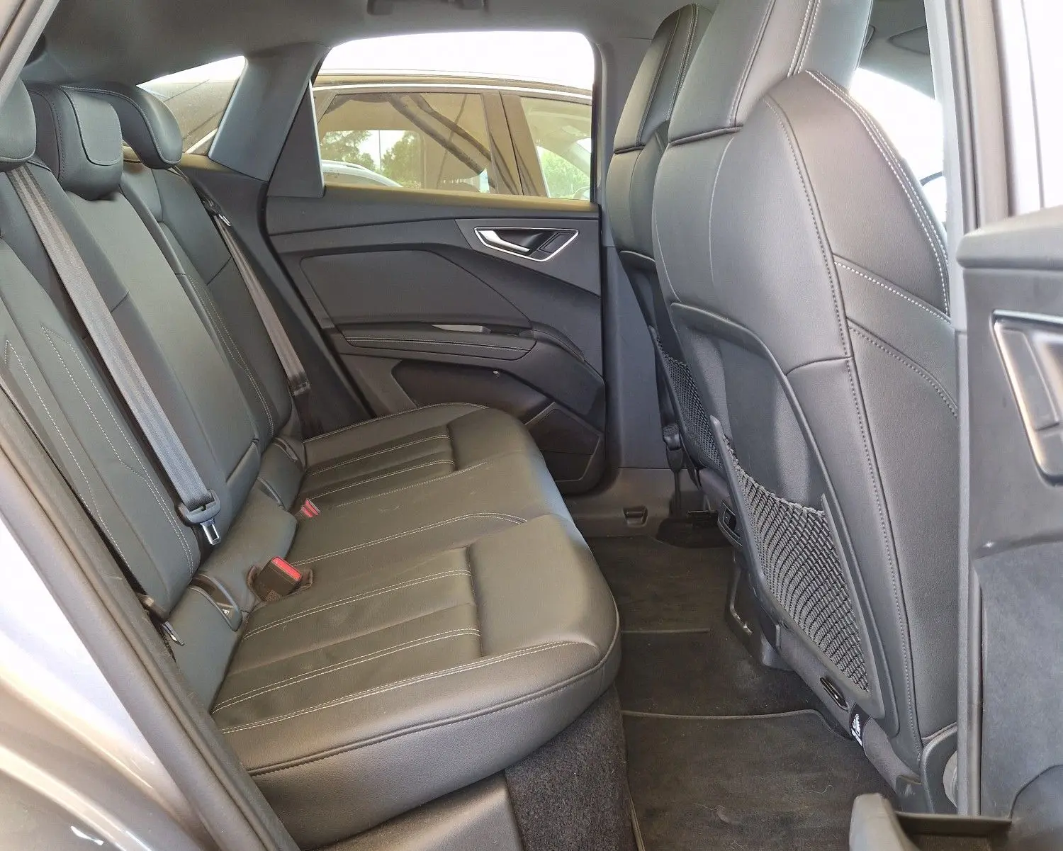Intérieur arrière de l'Audi Q4 E-TRON SPORTBACK gris thyphon, vue côté gauche avec sièges en cuir noir et toit ouvrant.