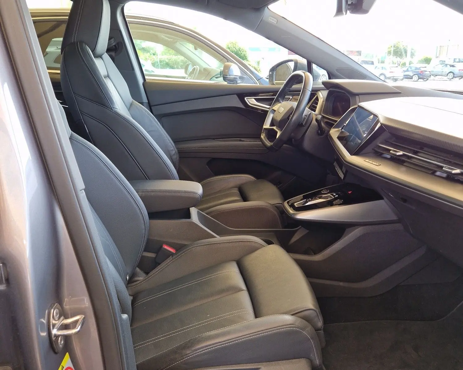 Intérieur côté conducteur de l'Audi Q4 E-TRON SPORTBACK gris thyphon 2022, sièges cuir noir et toit ouvrant panoramique.