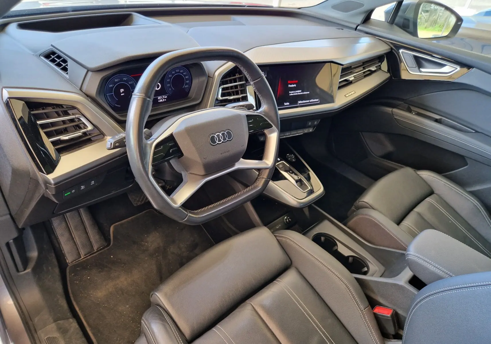 Intérieur noir de l'Audi Q4 E-TRON Sportback 50 quattro 2022, vue côté conducteur sur tableau de bord et volant multifonction.