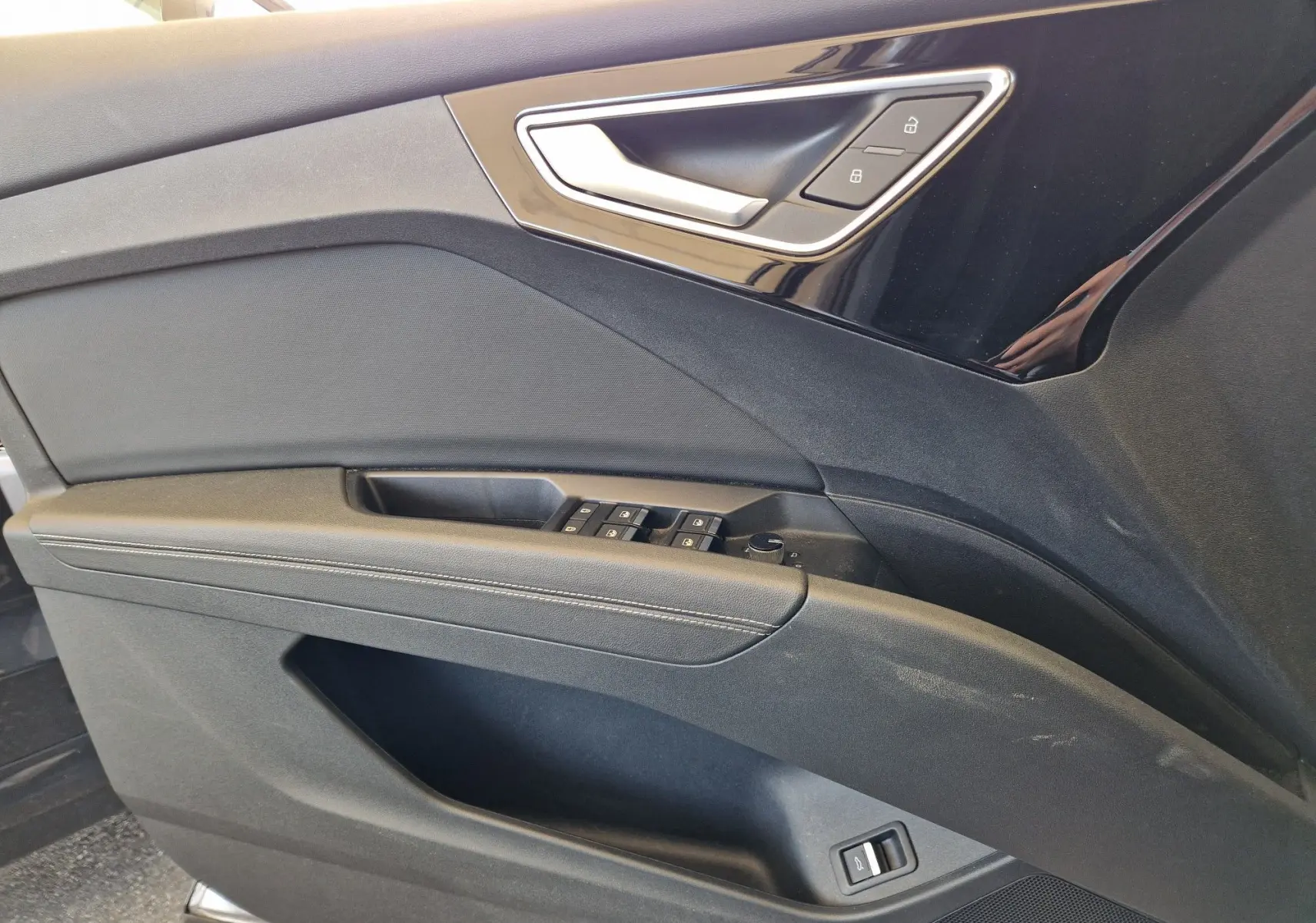 Détail de la porte côté gauche de l'Audi Q4 E-TRON Sportback gris thyphon avec commandes de vitres et verrouillage.