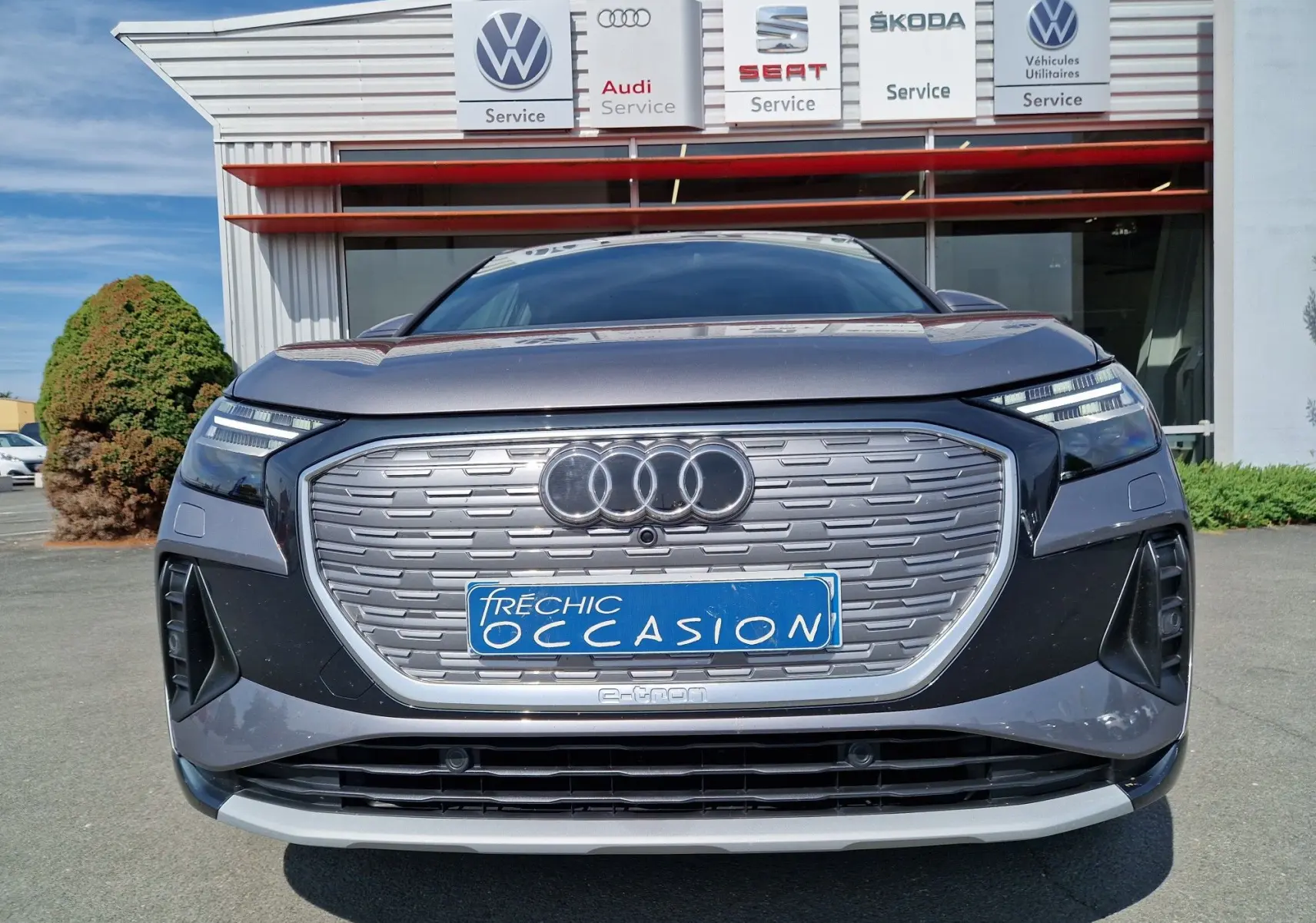 Vue frontale d'un Audi Q4 E-TRON SPORTBACK gris thyphon avec calandre fermée et logo Audi lumineux.