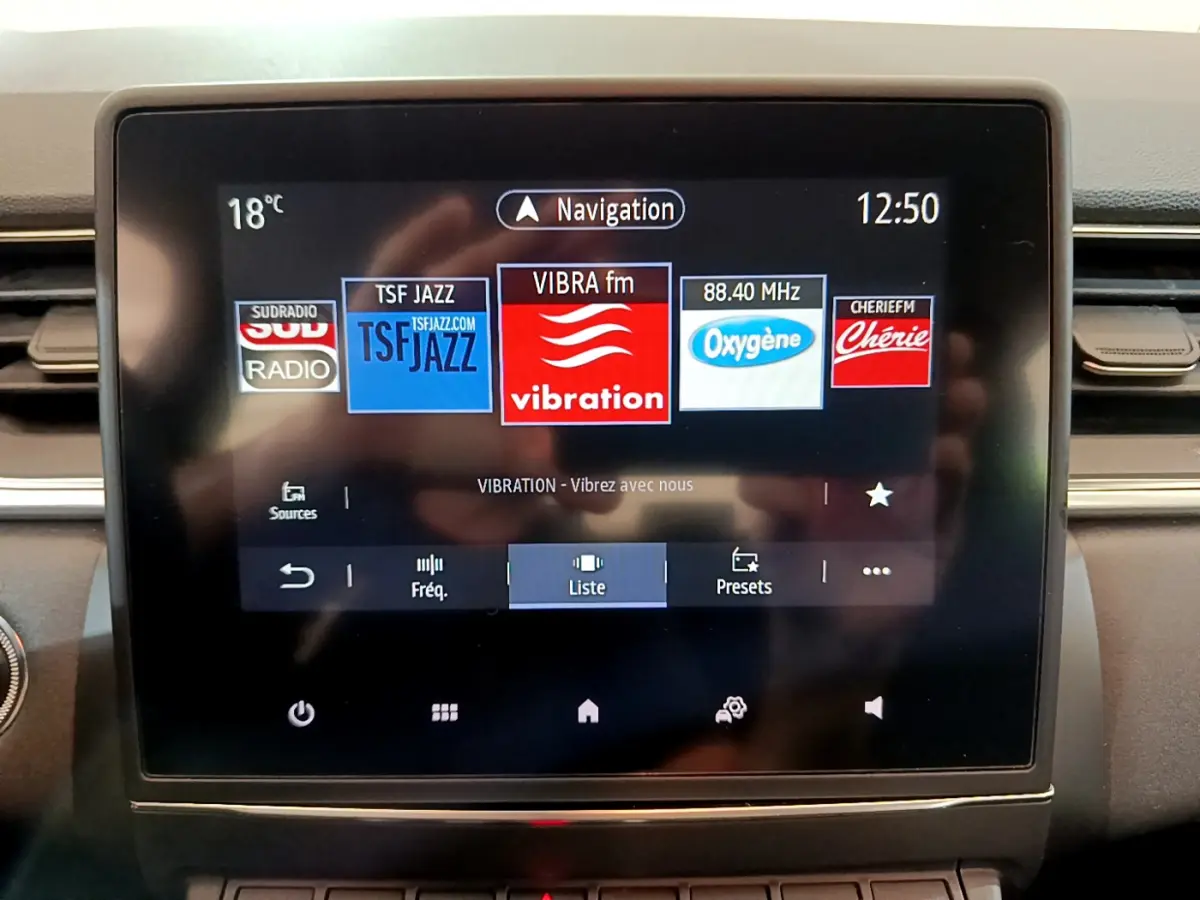 Écran tactile central du tableau de bord du Renault Captur Business Blue dCi 95, affichant les radios FM en mode navigation.