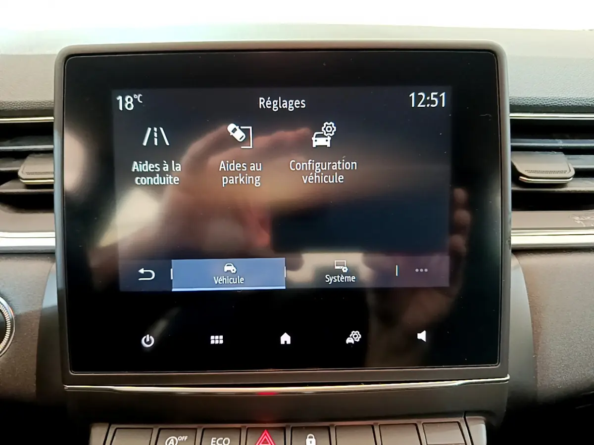 Écran tactile central du tableau de bord du Renault Captur Business noir, affichant les réglages d’aide à la conduite et parking.