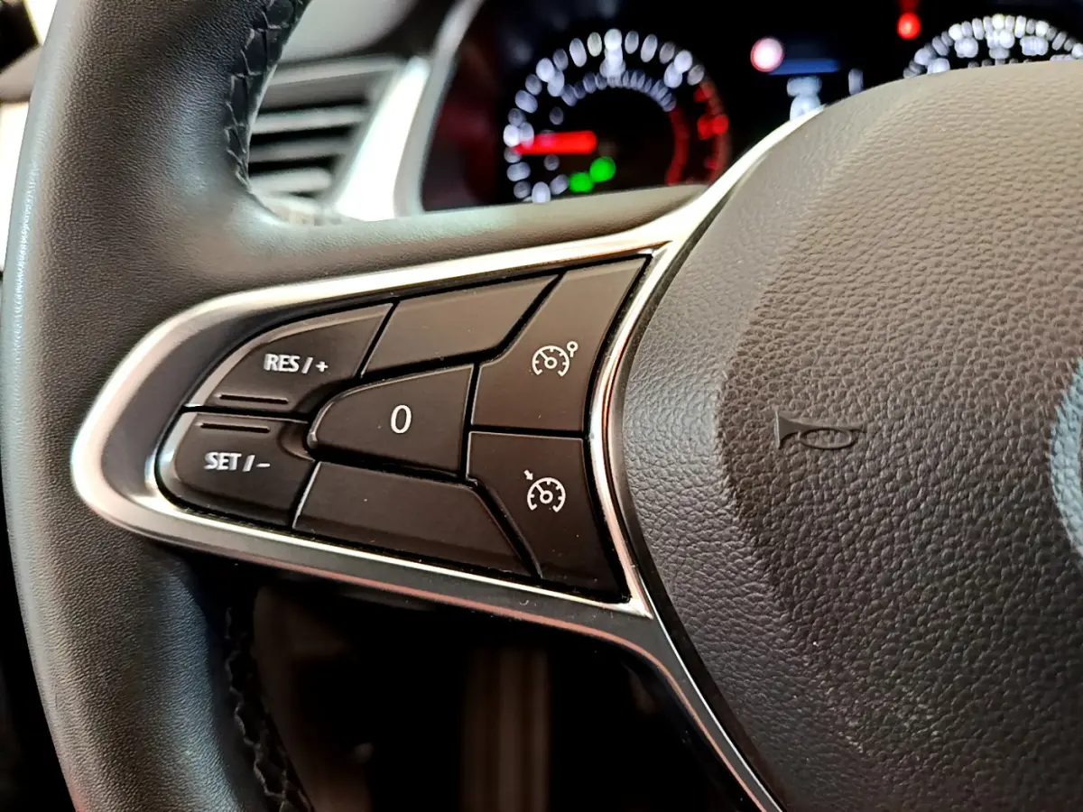 Gros plan sur les commandes du régulateur de vitesse à gauche du volant noir du Renault Captur Business 2020.