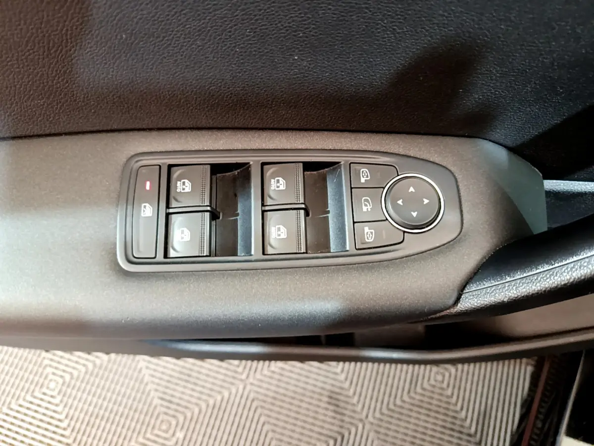 Gros plan sur les commandes de lève-vitres et rétroviseurs côté conducteur d'un Renault Captur noir 2020.