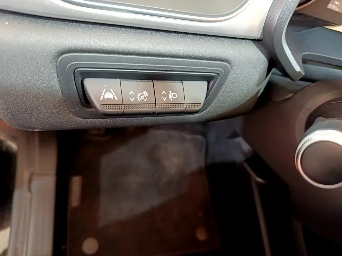 Gros plan sur les commandes d'assistance à la conduite sous le tableau de bord du Renault Captur Business noir de 2020.